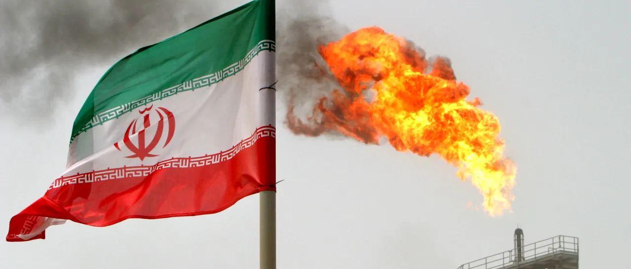 A gas flare on an oil production platform in the Soroush oil fields is seen alongside an Iranian flag in the Persian Gulf, Iran, July 25, 2005. REUTERS/Raheb Homavandi - RC170D19B320