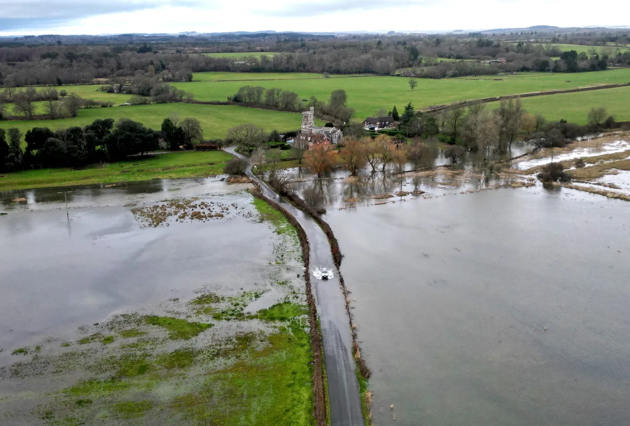 An aerial view shows a car crossing a flooded road in Harbridge, southern England on January 28, 2025 (Photo by HENRY NICHOLLS / AFP) (Photo by HENRY NICHOLLS/AFP via Getty Images)