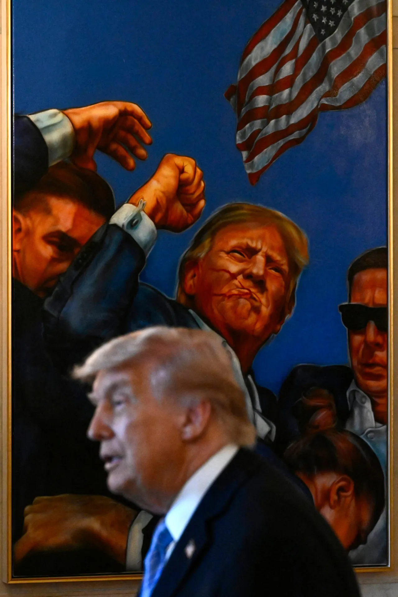 US President Donald Trump is pictured backdropped by a painting depicting his 2024 assassination attempt in Pennsylvania, as he participates in a Small Business Summit in the East Room of the White House in Washington, DC on May 4, 2026. (Photo by Kent NISHIMURA / AFP via Getty Images)