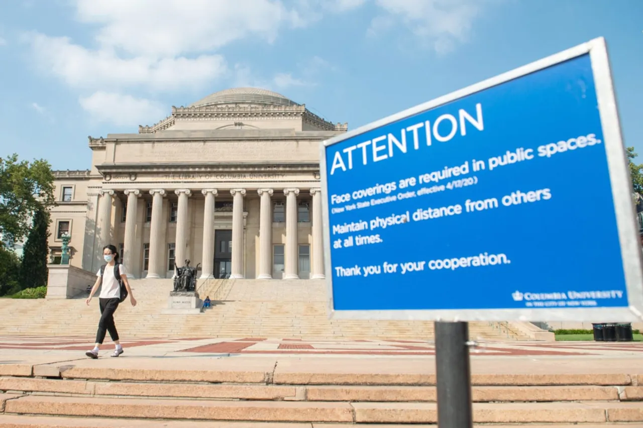 NEW YORK, NEW YORK - AUGUST 06: A woman wearing a mask walks near a COVID-19 related instructional 'attention' sign at Columbia University as the city continues Phase 4 of re-opening following restrictions imposed to slow the spread of coronavirus on August 06, 2020 in New York City. The fourth phase allows outdoor arts and entertainment, sporting events without fans and media production. (Photo by Alexi Rosenfeld/Getty Images)
