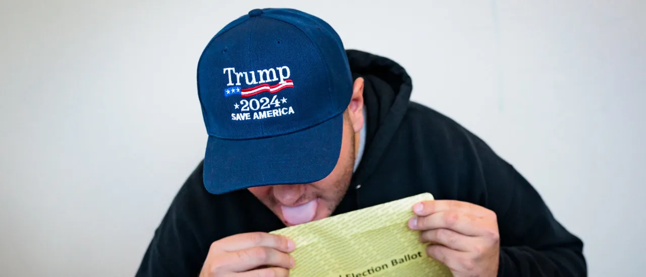 DOYLESTOWN, PENNSYLVANIA - OCTOBER 15: Kenny Laureno, 24, seals their official election ballot while voting "On Demand" using an absentee or mail-in ballot on October 15, 2024 in Doylestown, Pennsylvania. Registered voters in Pennsylvania can vote "On Demand" by requesting, a mail-in or absentee ballot filing it out and dropping it off all in one visit to their county election office or other designated location. (Photo by Hannah Beier/Getty Images)