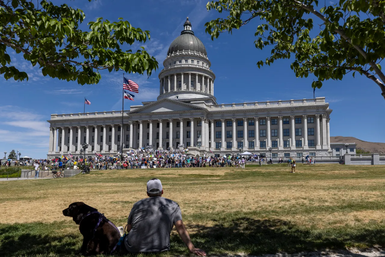 A man and his dog look at a demonstration at the Utah State Capitol to oppose the construction of the Stratos data center in Box Elder County on May 23, 2026 in Salt Lake City, Utah. The proposed data center would be about 40,000 acres and is speculated to use 9 gigawatts of power. (Photo by Natalie Behring/Getty Images)