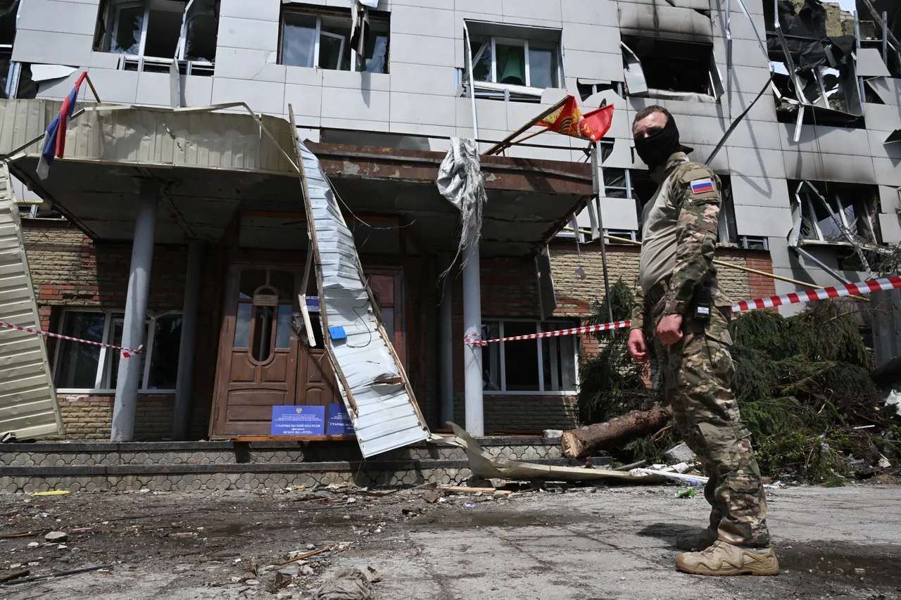 A Russian service member stands in front of what is presented by Russian authorities as the destroyed dormitory building of the Starobilsk professional college of the Luhansk Pedagogical University, following a drone attack in Starobilsk, Russian-controlled Ukraine, on May 24, 2026. (Photo by Igor IVANKO / AFP via Getty Images)