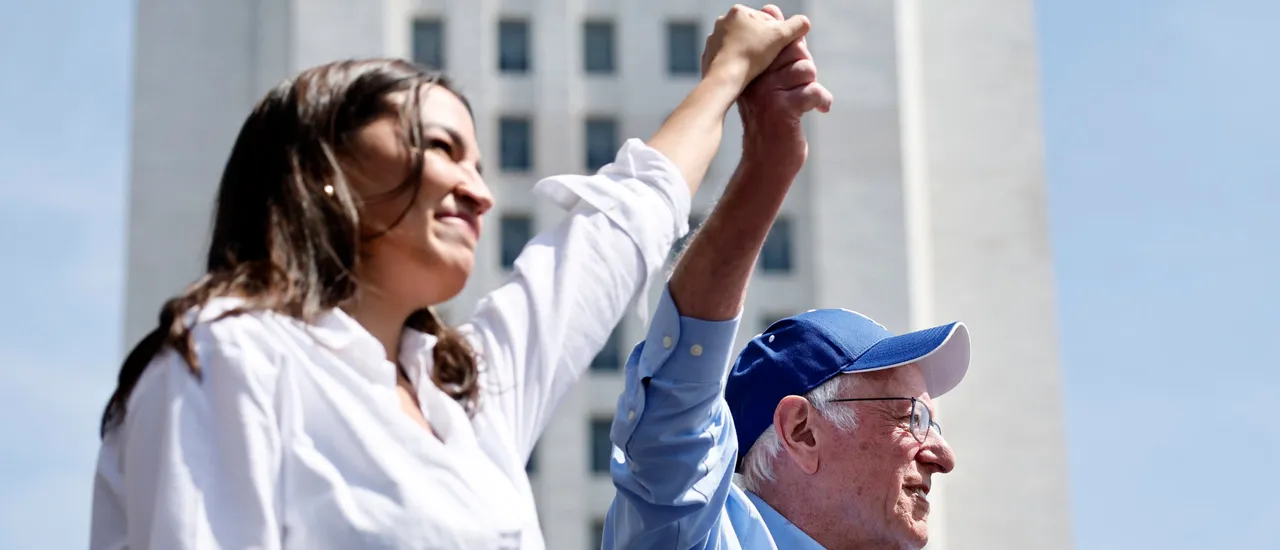 LOS ANGELES, CALIFORNIA - APRIL 12: U.S. Sen. Bernie Sanders (I-VT) and Rep. Alexandria Ocasio-Cortez (D-NY) hold hands during a stop on their ‘Fighting Oligarchy’ tour at Grand Park on April 12, 2025 in Los Angeles, California. An estimated 36,000 people attended the rally which also saw Neil Young and Joan Baez perform. (Photo by Mario Tama/Getty Images)