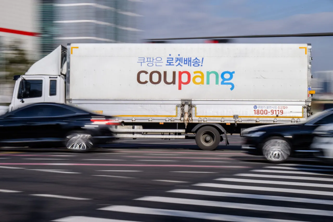 A delivery truck of South Korean e-commerce giant Coupang is driven along a road in Seoul on December 9, 2025. South Korean police raided the Seoul headquarters of e-commerce giant Coupang on December 9, over a recent data leak believed to have affected almost two-thirds of the country's population. (Photo by ANTHONY WALLACE / AFP via Getty Images)