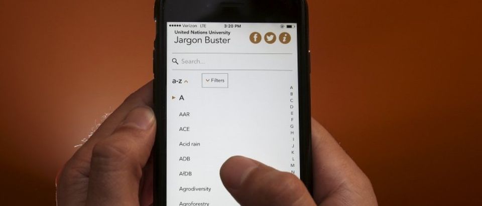 A man poses with an iPhone that displays the UNU Jargon Buster App in this photo illustration in the Manhattan borough of New York