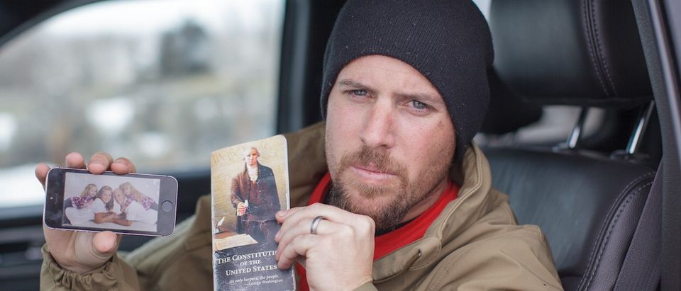 Jon Ritzheimer, 32, shows a family picture on his phone and a copy of the US Constitution to the media at the Malheur National Wildlife Refuge Headquarters near Burns, Oregon, January 4, 2016. The FBI on January 4 sought a peaceful end to the occupation by armed anti-government militia members at a US federal wildlife reserve in rural Oregon, as the standoff entered its third day. The loose-knit band of farmers, ranchers and survivalists -- whose action was sparked by the jailing of two ranchers for arson -- said they would not rule out violence if authorities stormed the site, although federal officials said they hope to avoid bloodshed. (ROB KERR/AFP/Getty Images)