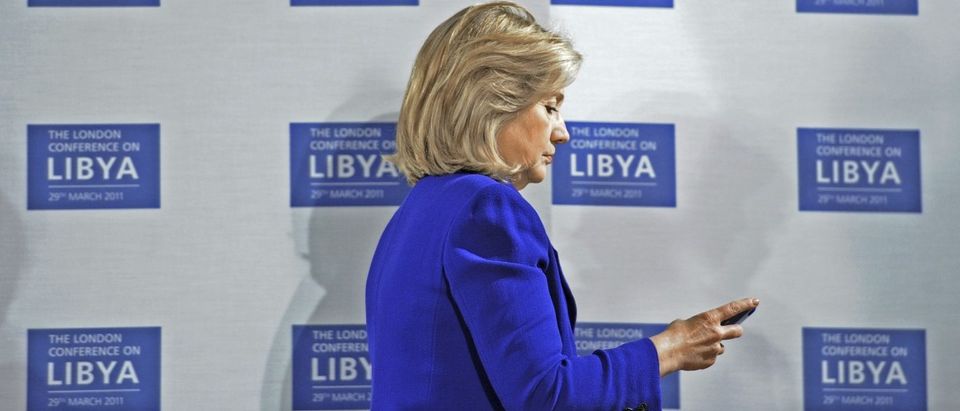 Secretary of State Hillary Clinton checks her mobile phone before a conference at the Foreign &amp; Commonwealth Office in London