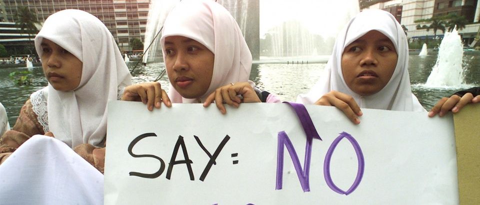 Indonesian women wearing Muslim hijab head scarves hold a sign denouncing calls by Muslim groups encouraging the practice of polygamy among government employees during a protest by a women's rights group in central Jakarta, November 24, 2000. Though Islam allows Muslim men up to four wives the practice is not common and the Indonesian government forbids its employees to have more than one wife. /REUTERS