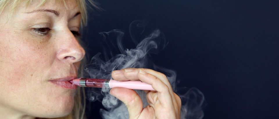 A woman smokes an e-cigarette as he visits Vapexpo, an international exhibition to promote e-cigarette, in Bordeaux, western France, on March 13, 2014. E-cigarettes are battery powered gadgets that deliver nicotine through a vapor that may be fruit or candy-flavored. AFP PHOTO / NICOLAS TUCAT (Photo credit should read NICOLAS TUCAT/AFP/Getty Images)