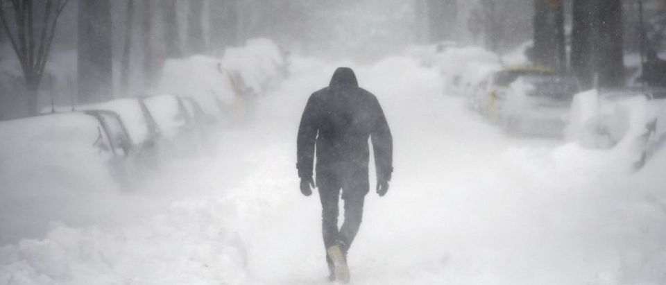 A man walks along a street covered by snow during a winter storm in Washington