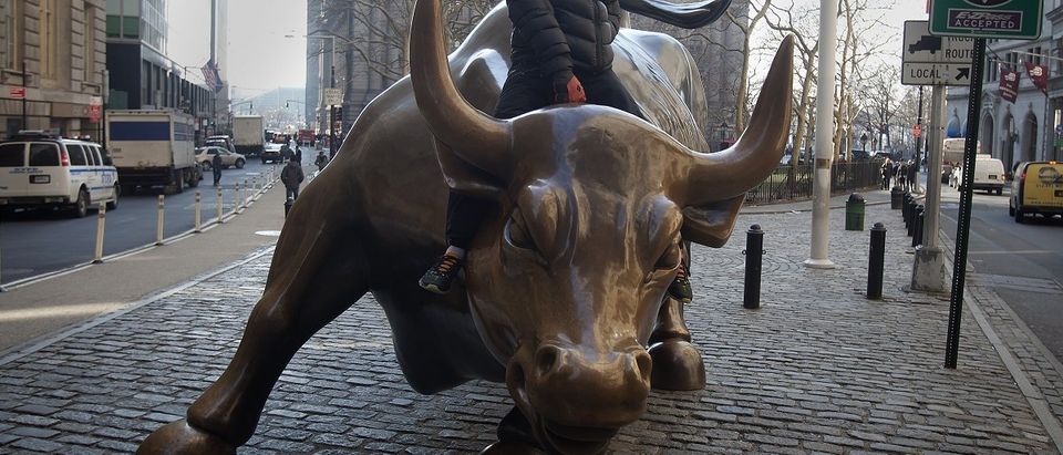 A tourist mounts the "Charging Bull" statue as he poses for a photo near Wall Street, in the Manhattan borough of New York