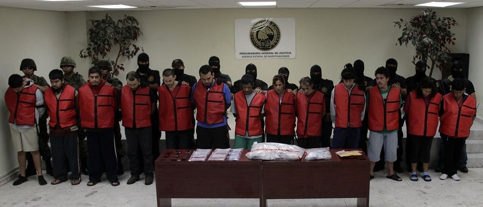 Police detectives escort members of the Zetas drug gang as they are presented to the media in Monterrey