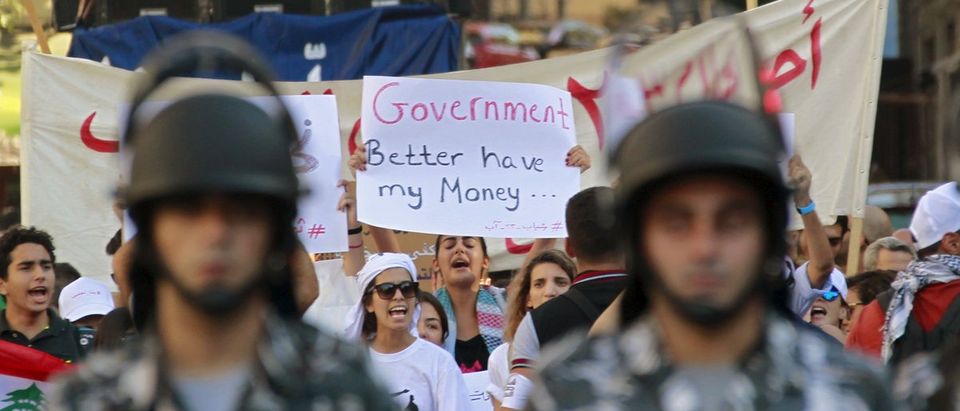 Lebanese security forces walk in front of protesters during a protest against corruption and against the government's failure to resolve a crisis over rubbish disposal in Beirut, Lebanon