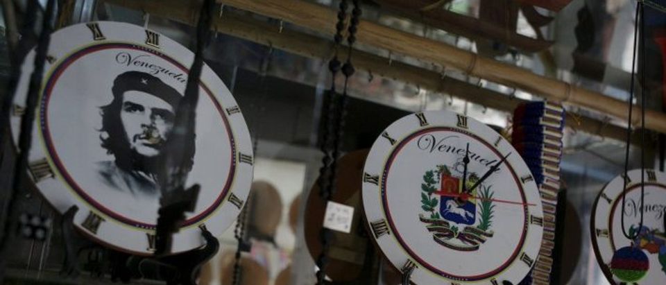 Wall clocks with Venezuela's shield, with country map and with a portrait of Ernesto "Che" Guevara are seen on a shelf at a store in Caracas
