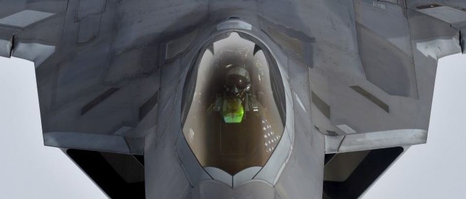A pilot looks up from a U.S. F-22 Raptor fighter as it prepares to refuel in mid-air with a KC-135 refuelling plane over European airspace during a flight to Britain from Mihail Kogalniceanu air base in Romania