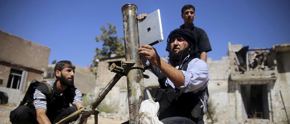 A member of the 'Ansar Dimachk' Brigade which operates under the Free Syrian Army uses an iPad during preparations to fire a homemade mortar in Jobar