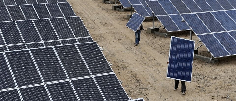 Employees carry solar panels at a solar power plant in Aksu