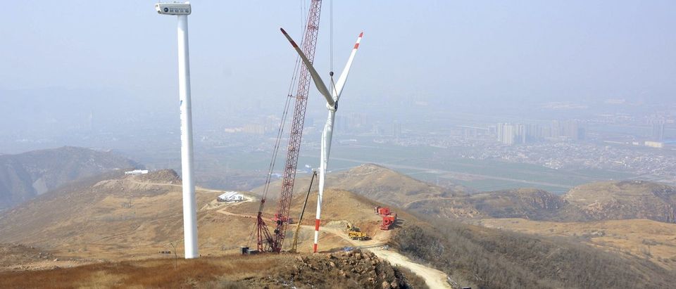 The rotor blades of a wind turbine is lifted by a crane at a construction site of a wind power plant in Yiyang