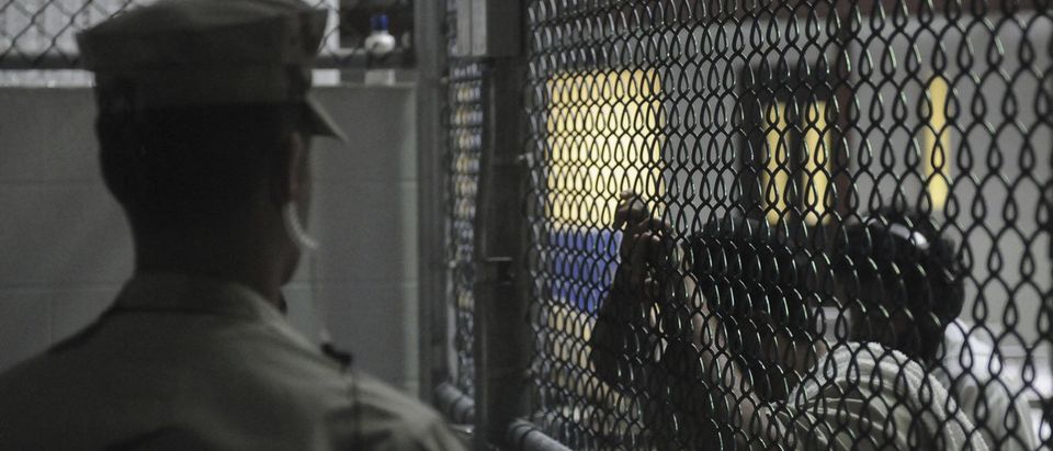 A Sailor stands watch over detainees in a cell block in Camp 6 at Guantanamo Bay naval base