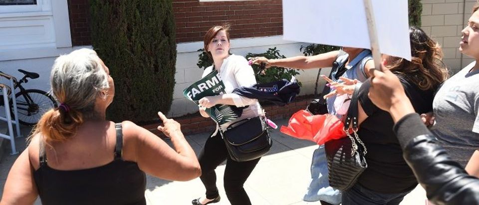 Protesters confront a woman, center, leaving a rally for Republican U.S. presidential candidate Donald Trump in Fresno