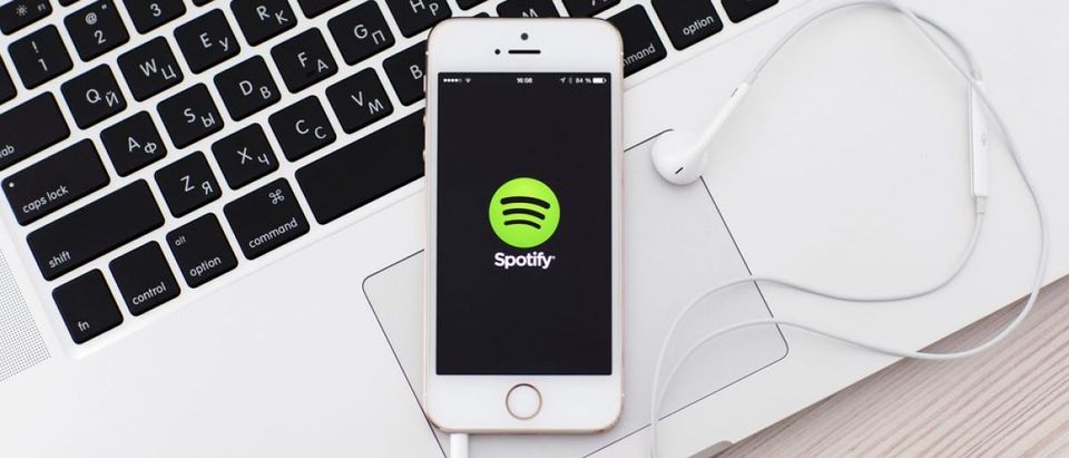 iPhone and Spotify, a Swedish music service that offers legal streaming music. On top of Apple computer. [Shutterstock - Denys Prykhodov]