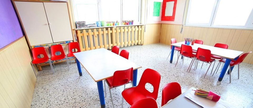Inside a classroom and day care center with school desks and small red chairs. [ChiccoDodiFC - Shutterstock]