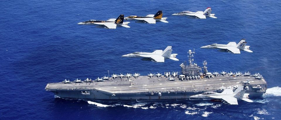A combined formation of aircraft from Carrier Air Wing (CVW) 5 and Carrier Air Wing (CVW) 9 pass in formation above the Nimitz-class aircraft carrier USS John C. Stennis (CVN 74) in the Philippine Sea