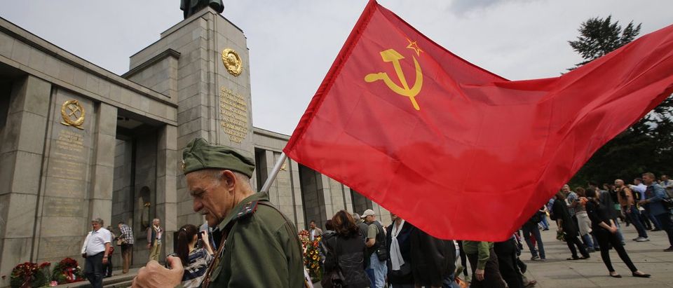 A man waering a Red Army uniform holds a Soviet flag during celebrations to mark Victory Day at the Soviet War Memorial near the Reichstag building, in Tiergarten district of Berlin