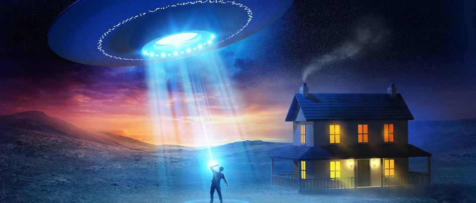 A person being abducted by aliens in front of his house. (Shutterstock/solarseven)