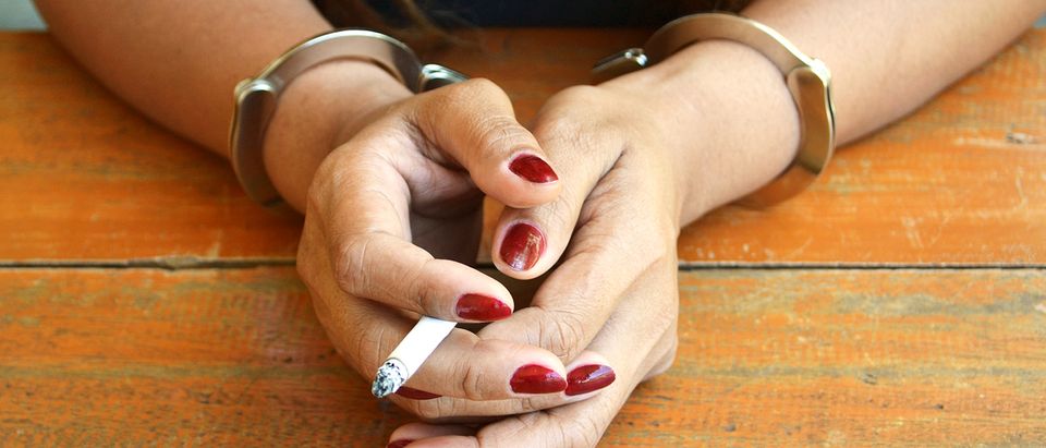 Woman Smokes A Cigarette While Handcuffed Photo:Shutterstock