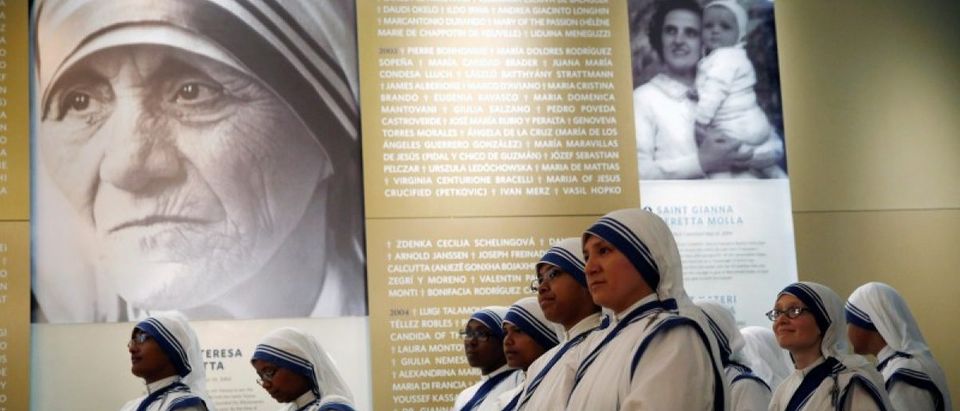 Members of Mother Teresa's order, the Missionaries of Charity, stand under a photograph before the unveiling of an official canonization portrait at the John Paul II National Shrine in Washington, U.S., September 1, 2016. REUTERS/Gary Cameron