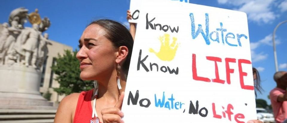 Heather Mendoza of Arlington, Virginia, holds up a sign as she protests outside the U.S. District Court in Washington, where a hearing was being held to decide whether to halt construction of an oil pipeline in parts of North Dakota where a Native American tribe says it has ancient burial and prayer sites, September 6, 2016. REUTERS/Kevin Lamarque
