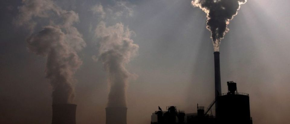 A coal-burning power plant can be seen behind a factory in the city of Baotou, in China's Inner Mongolia Autonomous Region October 31, 2010. REUTERS/David Gray/File Photo