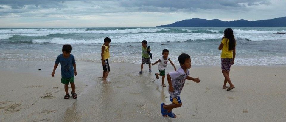 Children play along an empty beach after Typhoon Haima struck Pagudpud