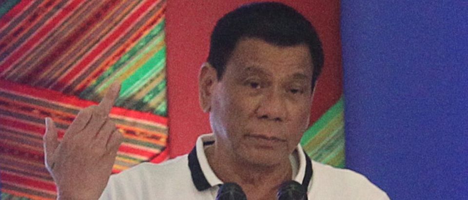Philippine President Rodrigo Duterte raises a middle finger thrust out in an obscene gesture as he speaks before local government officials in Davao