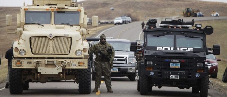 A North Dakota law enforcement officers stands next to two armored vehicles just beyond the police barricade on Highway 1806 near a Dakota Access Pipeline construction site. REUTERS/Josh Morgan