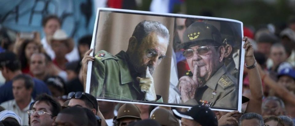 Attendees hold portraits of Cuba's late President Fidel Castro and current President Raul Castro as they pay tribute at a massive rally in Havana