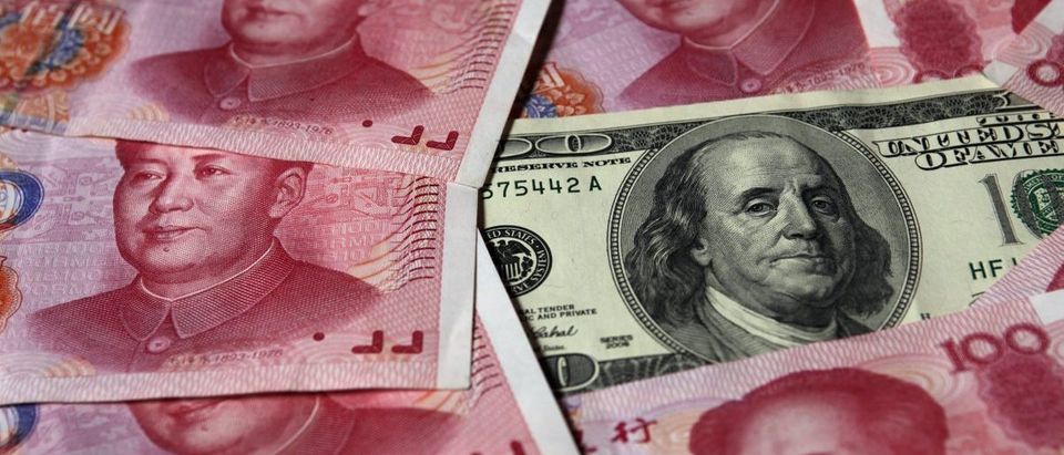 A U.S. $100 banknote is placed next to 100 yuan banknotes in this picture illustration taken in Beijing