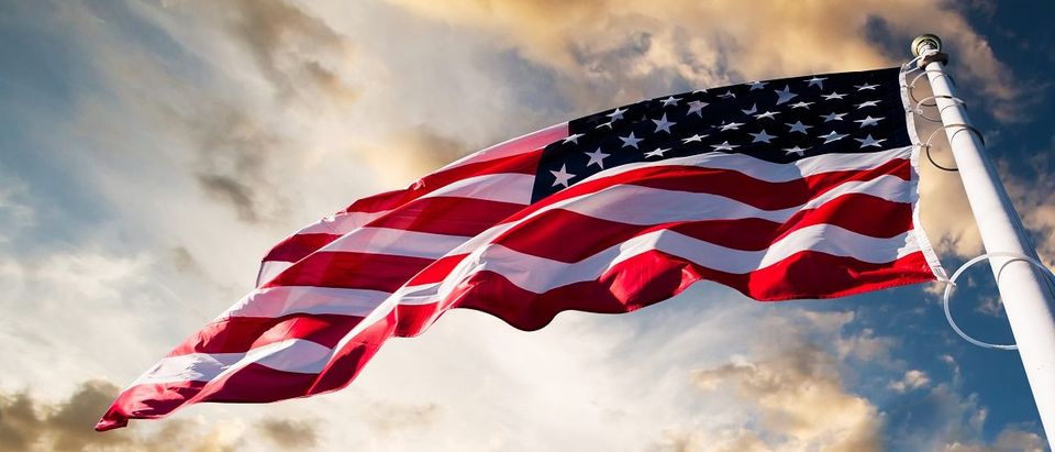 An American flag against a sky background. (Green/Shutterstock).