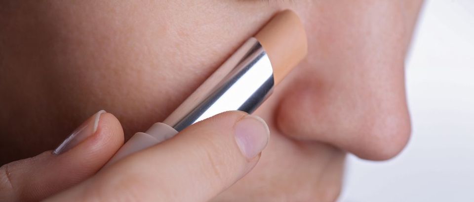 Woman applying corrector stick or concealer, cover dark circles under eyes. (Photo: Shutterstock)