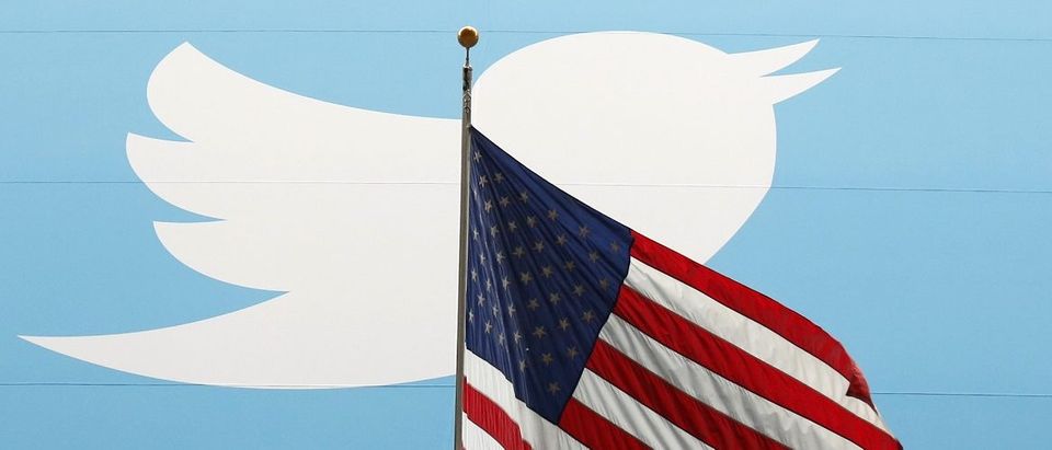 The Twitter Inc. logo is shown with the U.S. flag during the company's IPO on the floor of the New York Stock Exchange in New York