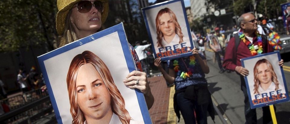 People hold signs calling for the release of imprisoned wikileaks whistleblower Chelsea Manning while marching in a gay pride parade in San Francisco, California