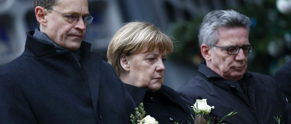 Berlin mayor Mueller, German Chancellor Merkel and German interior minister de Maiziere stand in silence at the Christmas market in Berlin