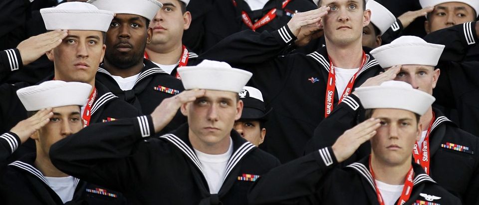 U.S. sailors salute during the retiring of the colors during the NCAA Carrier Classic men's college basketball game between Michigan State Spartans and North Carolina Tar Heels in Coronado,