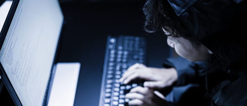 Hooded computer hacker stealing information with laptop. [Shutterstock - PORTRAIT IMAGES ASIA BY NONWARIT]