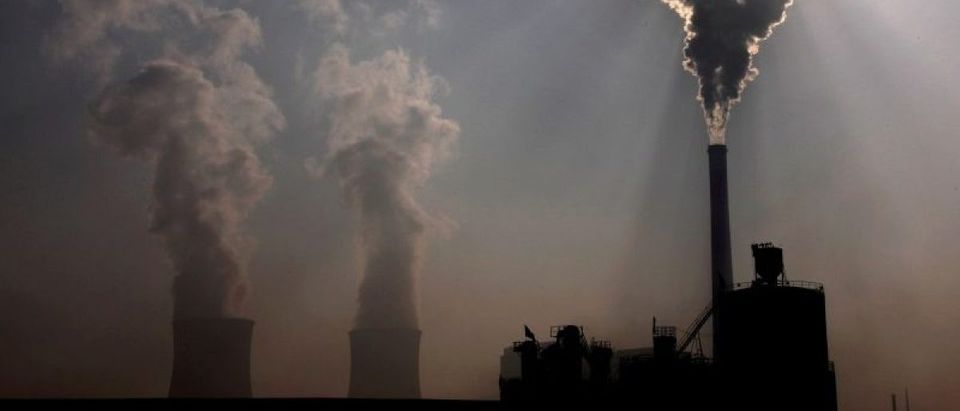 FILE PHOTO - A coal-burning power plant can be seen behind a factory in the city of Baotou, in China's Inner Mongolia Autonomous Region