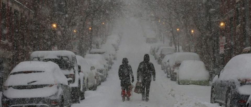 Pedestrians walk up a street on Beacon Hill during white-out, blizzard-like conditions in a winter nor'easter snow storm in Boston