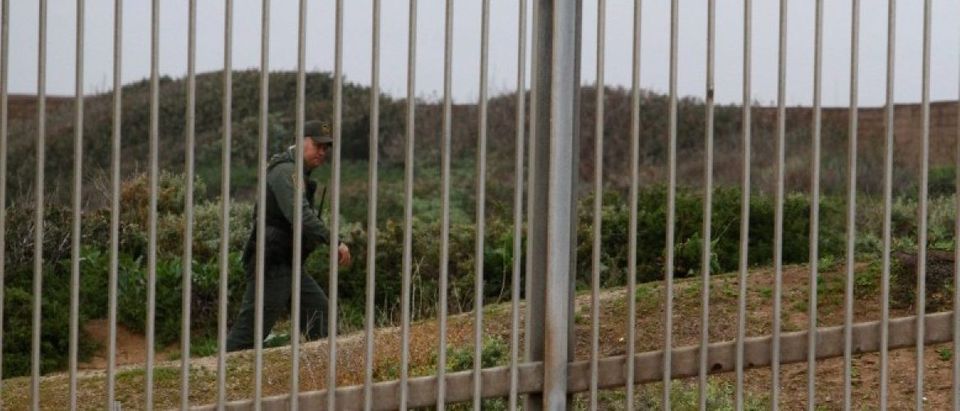 A U.S. Border Patrol agent is seen through the border fence between the United States and Mexico as photographed from Tijuana