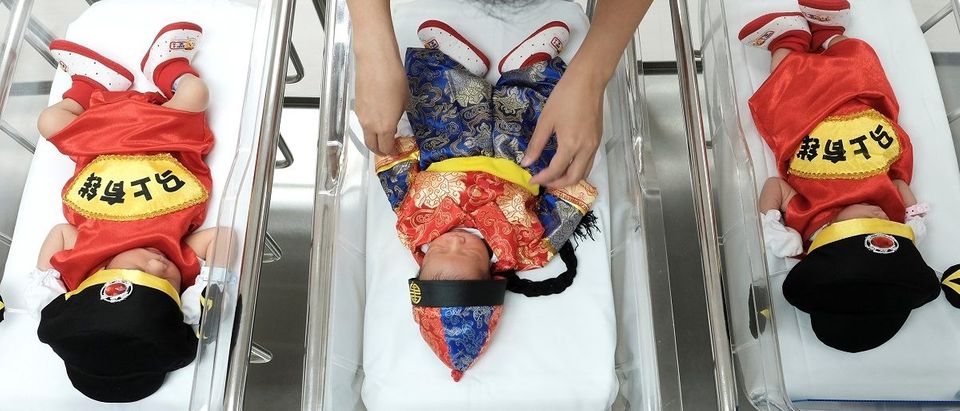A nurse takes care of newborn babies wearing Chinese traditional costumes to celebrate the Chinese New Year at the nursery room of Paolo Chockchai 4 Hospital, in Bangkok